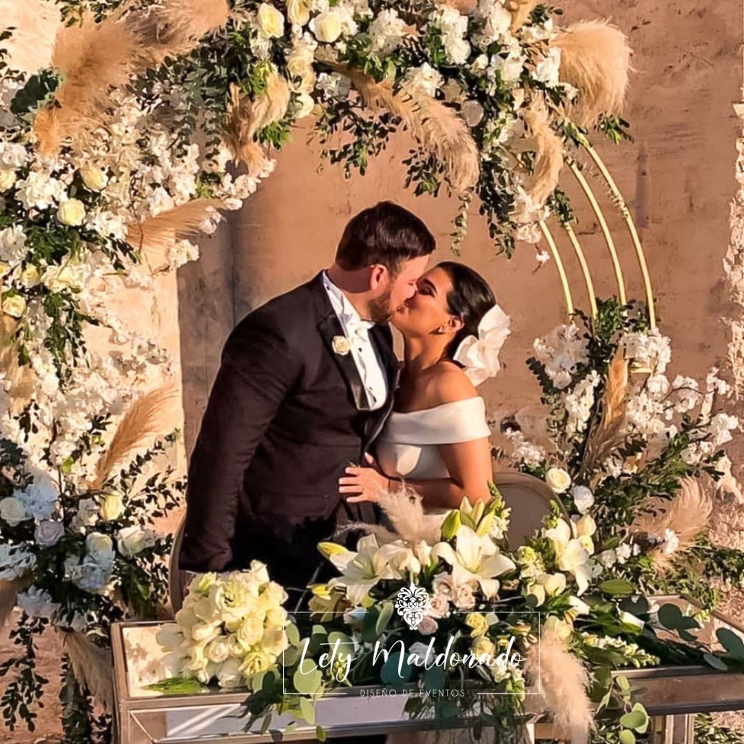 Beso de novios en arco floral